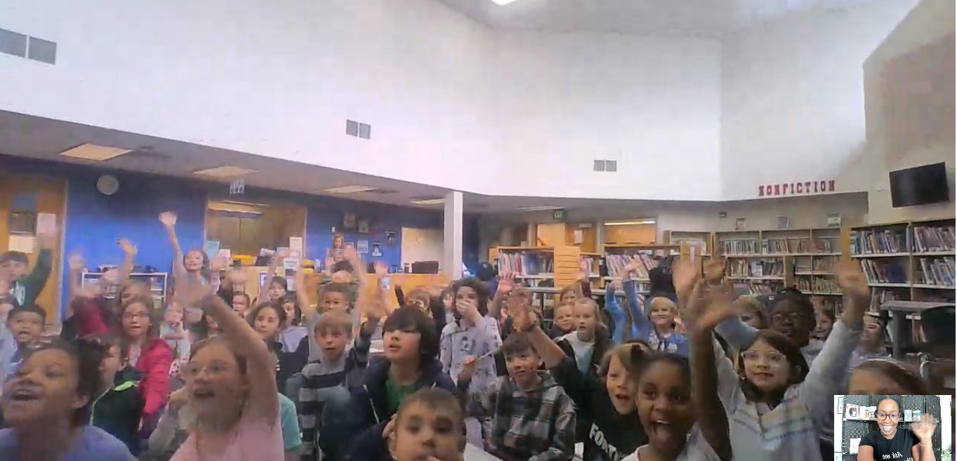 Virtual reading with a Colorado classroom, students with hands raised